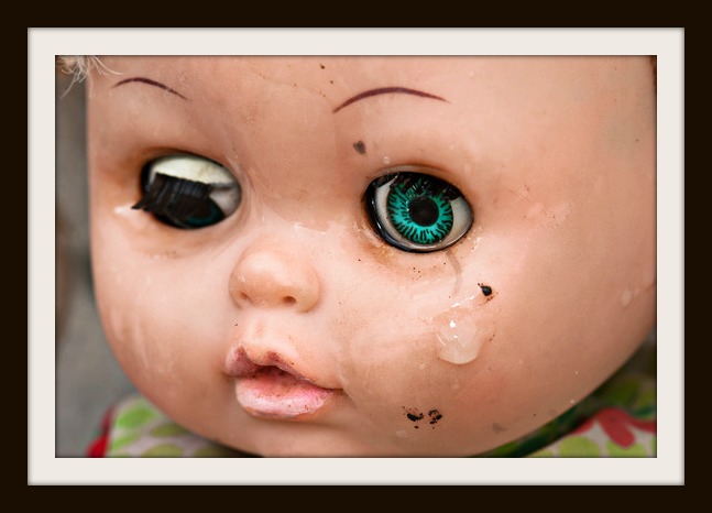 Concept: Abandoned Person. Close up of an old doll`s face with tear